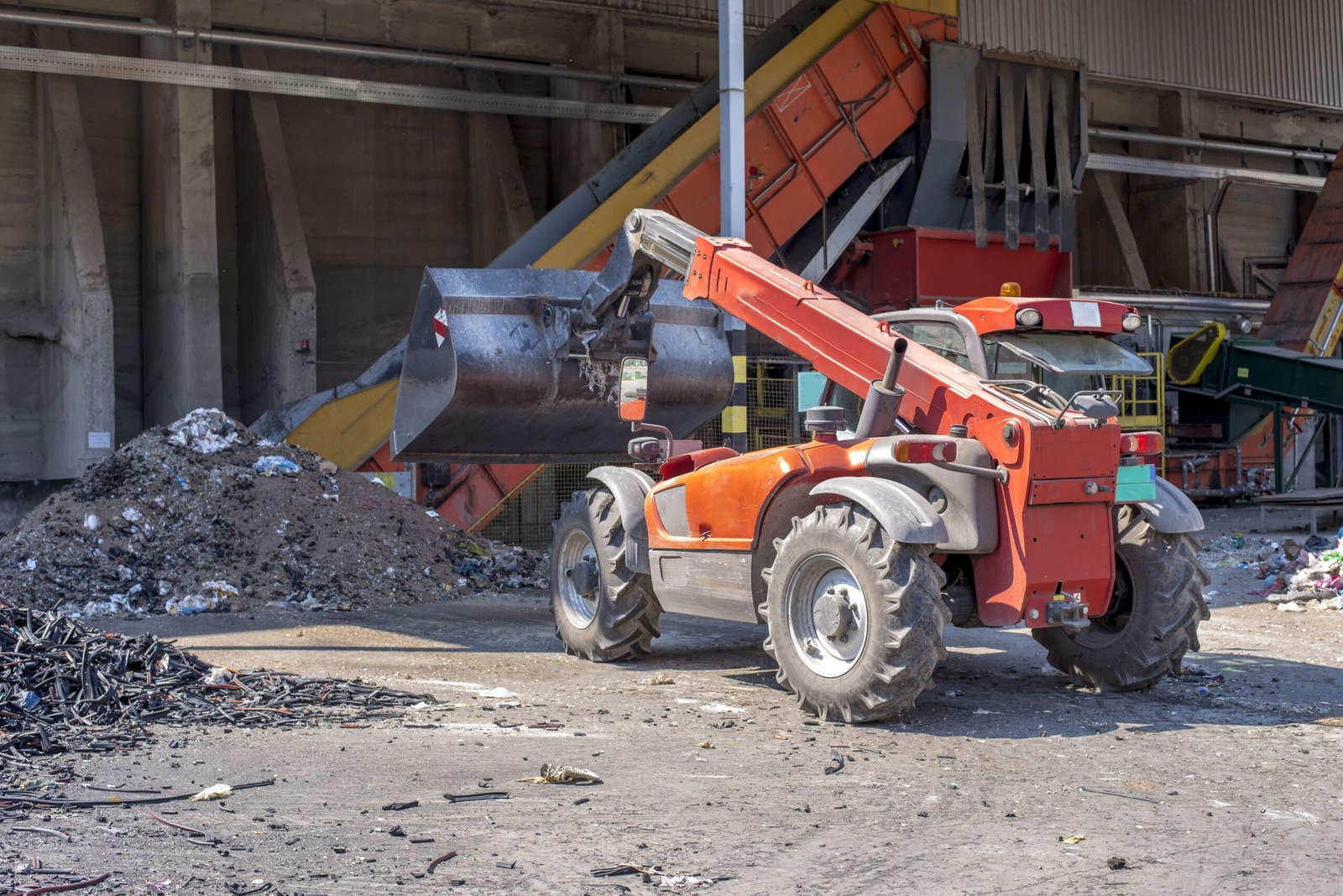 Loader transporting soil and waste materials at a waste treatment plant